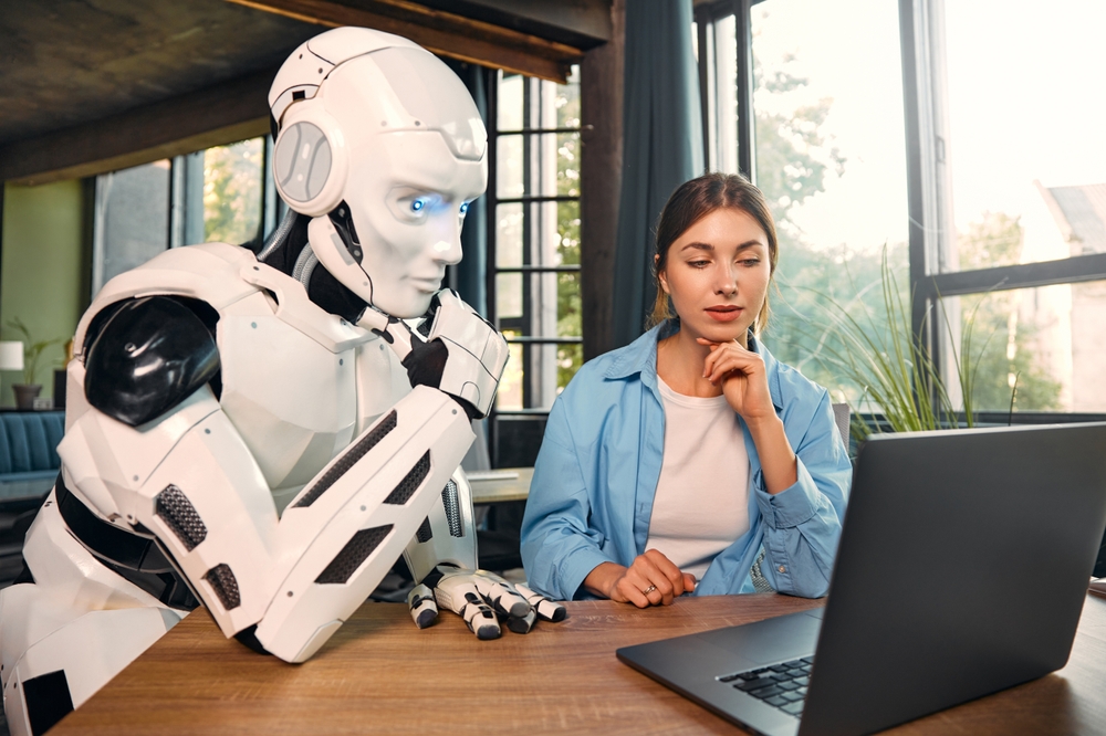 Young,Woman,And,A,Humanoid,Robot,Working,While,Sitting,At